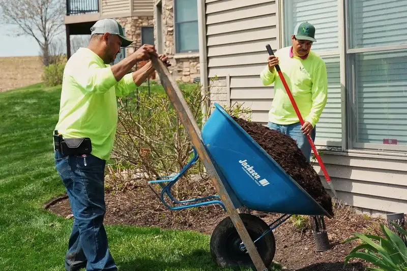 Two crew members spreading mulch from a wheelbarrow