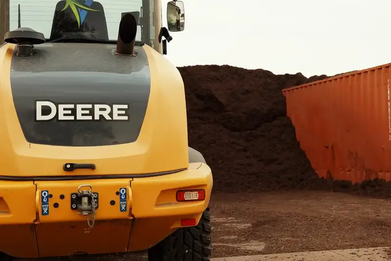 John Deere loader bucket next to a pile of mulch