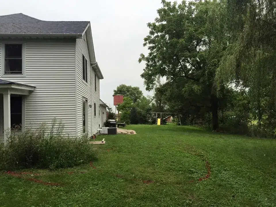 Before: open lawn beside a white house with no patio