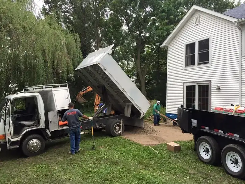 Truck delivering base rock while the crew spreads it