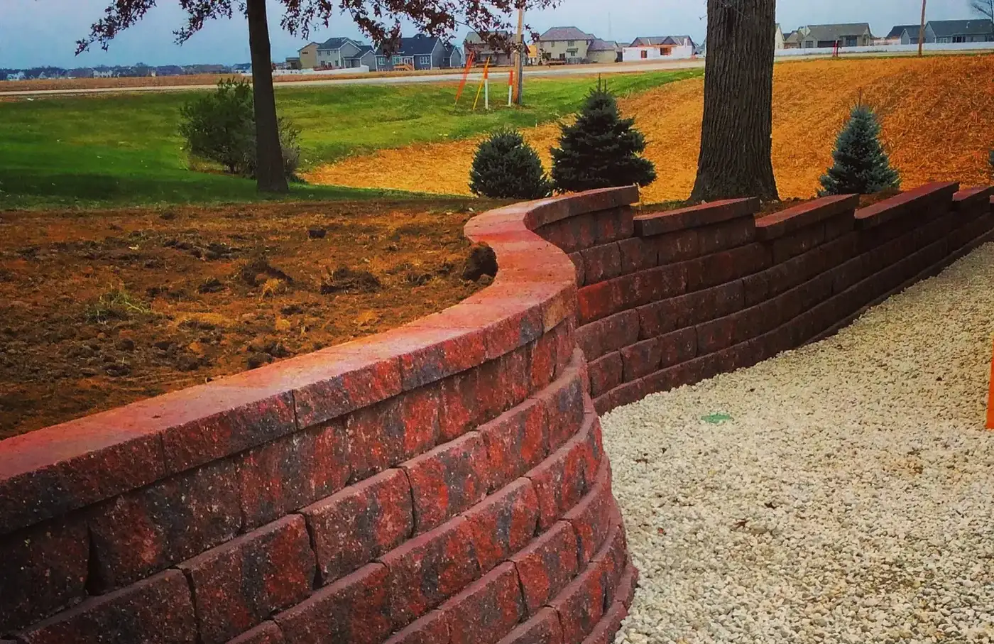 Curved red segmental block retaining wall along a gravel path