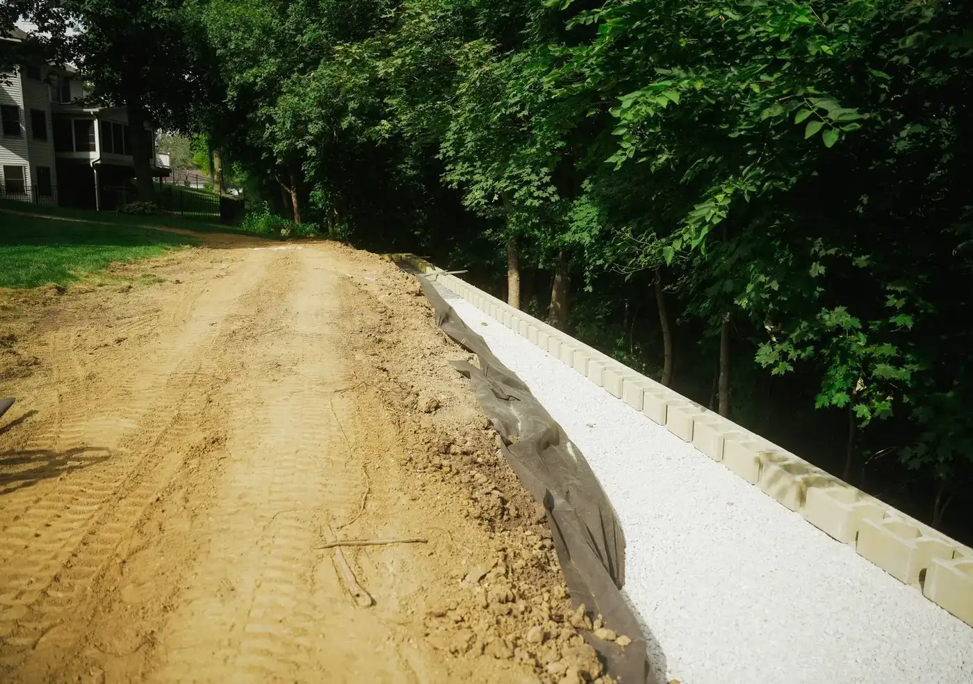Excavated trench with a compacted gravel base along a wooded slope
