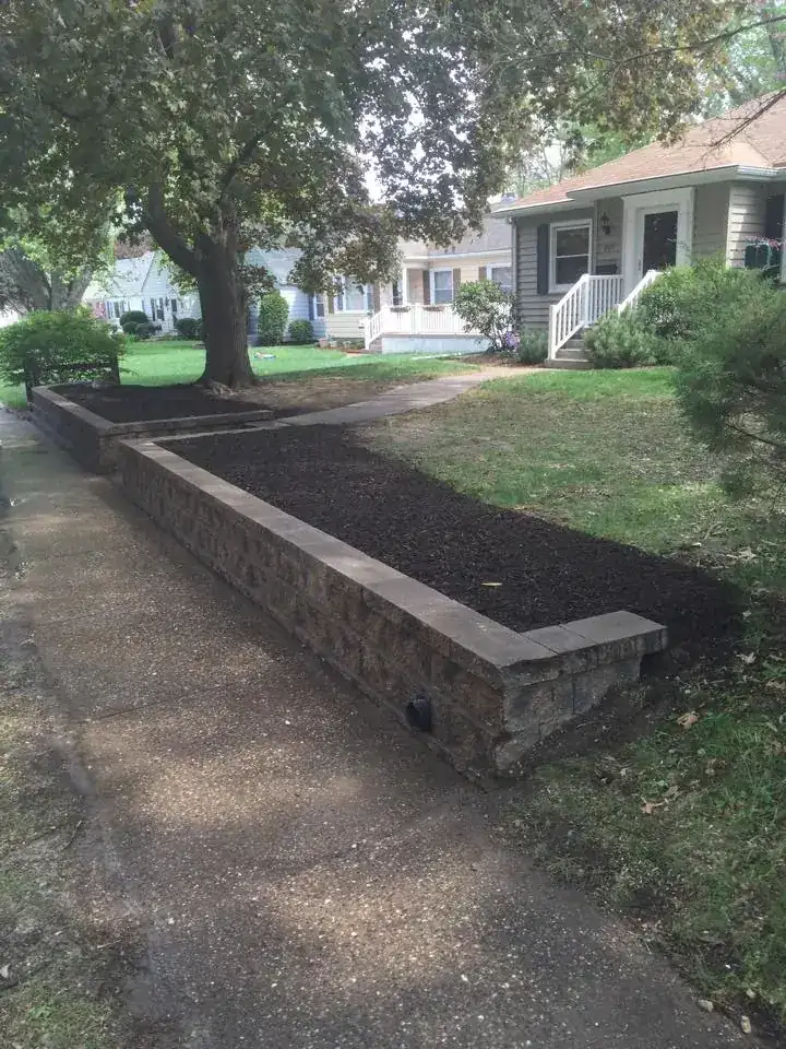Low block retaining wall along a residential sidewalk with fresh soil behind it