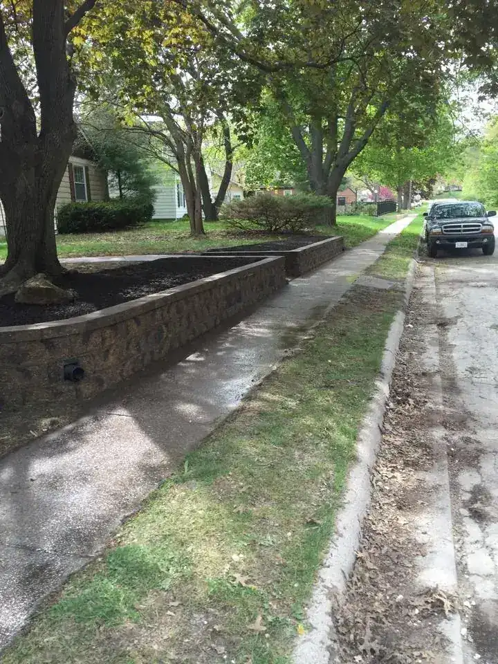 Block wall and new drainage along a sloped front yard beside a street