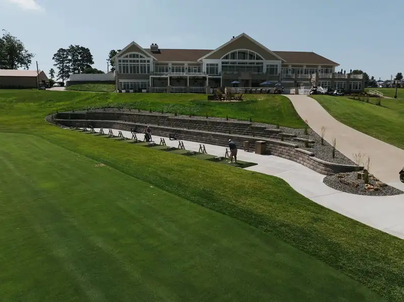 Terraced retaining walls stepping down a lawn below a large clubhouse