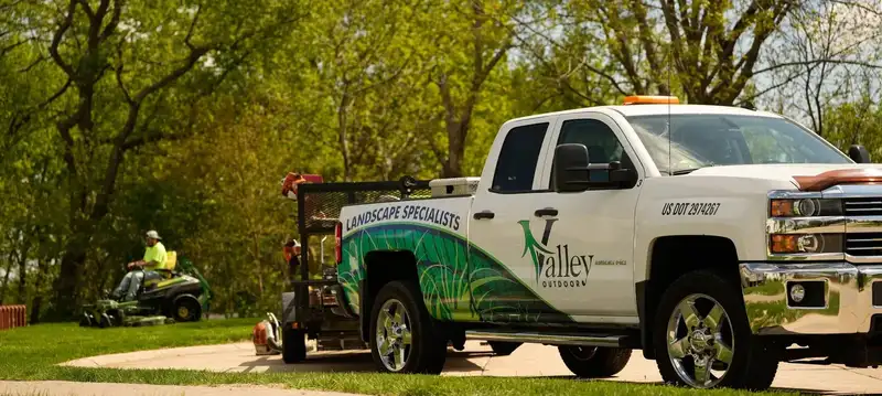 White Valley Outdoor pickup with green and blue lettering pulling a mower trailer