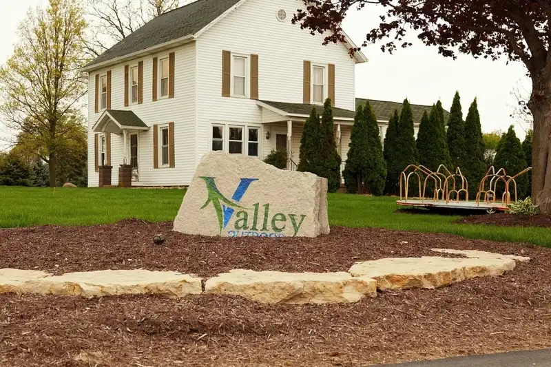 Valley Outdoor stone sign in a freshly landscaped front yard with new beds and a white farmhouse